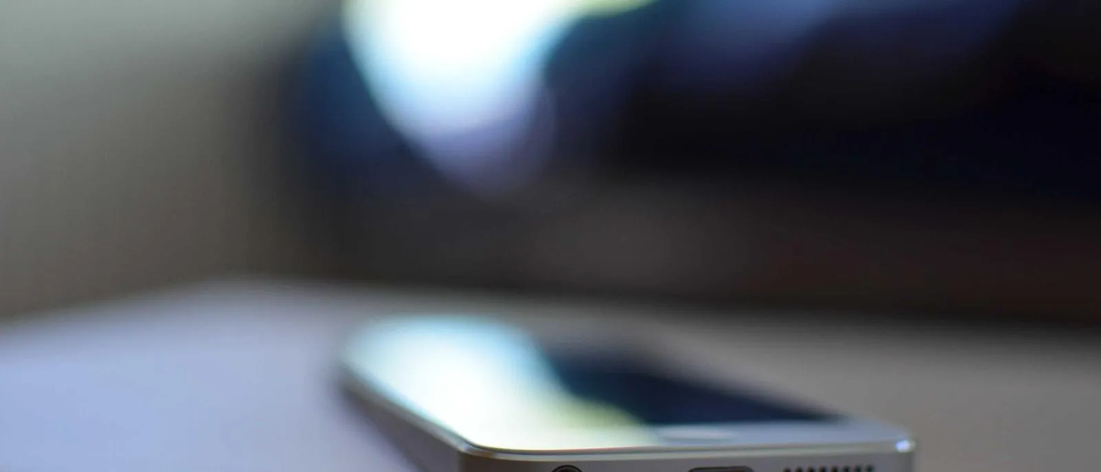 Smartphone liegt auf einem Tisch, weiches Licht